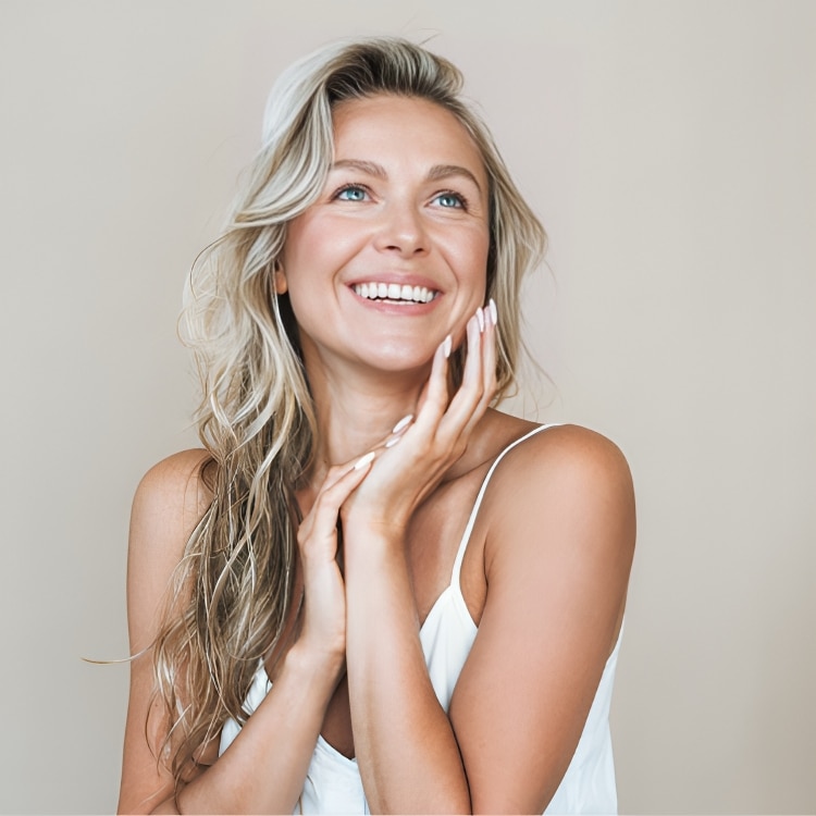 Woman smiling with hands near face against neutral background for dental practice