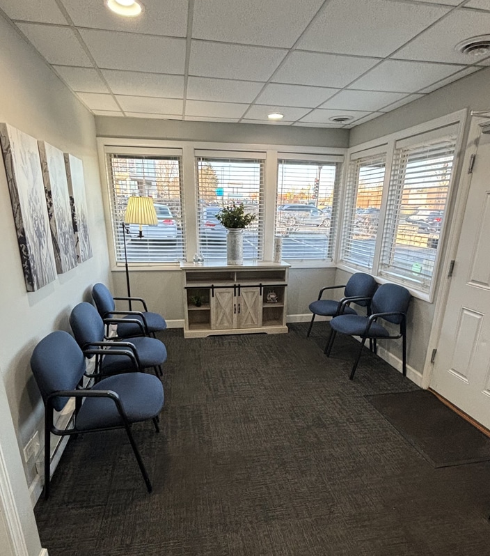 Waiting room with blue chairs, windows, and neutral decor at dental office.