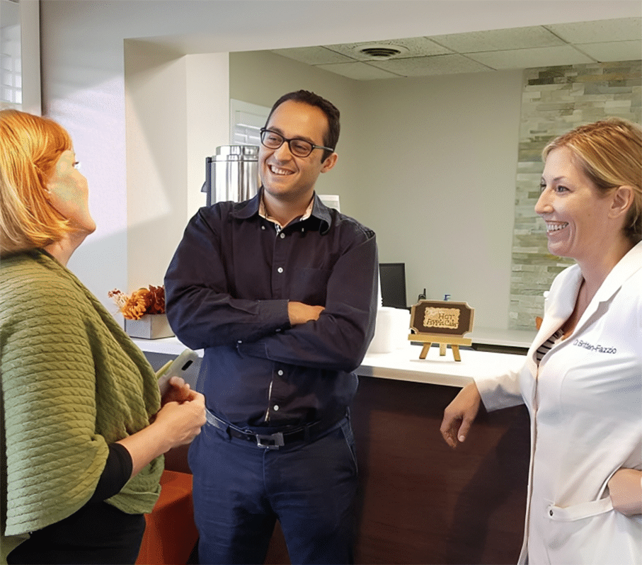 Three professionals having a discussion in a dental office interior setting.