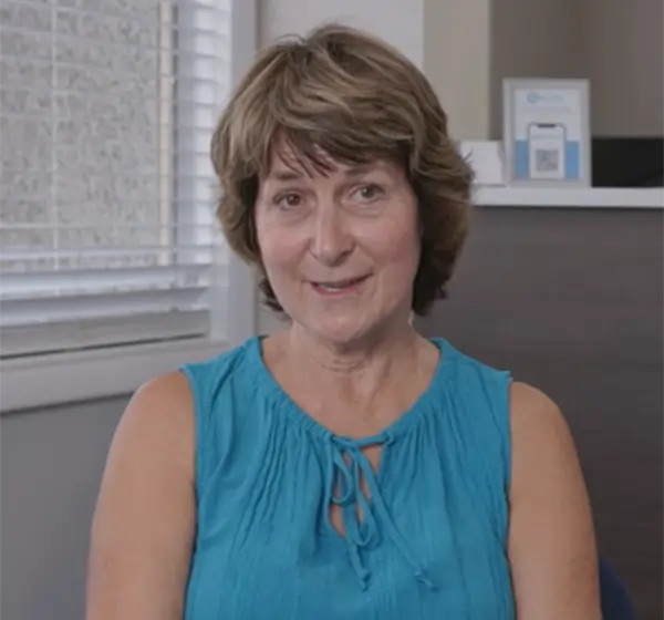 Woman smiling in dental office wearing teal sleeveless top