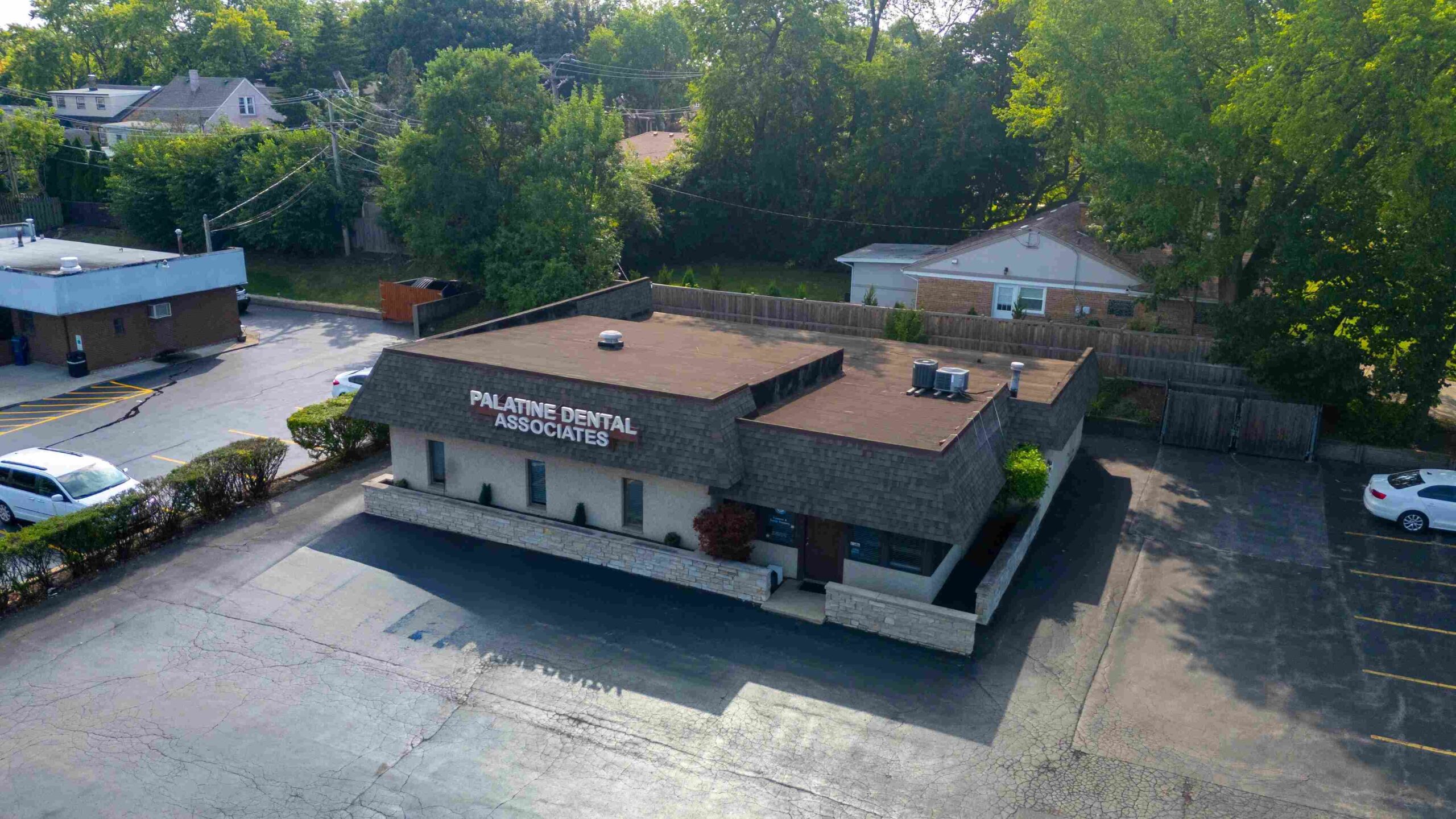 Aerial view of Palatine Dental Associates building surrounded by trees and parking area.