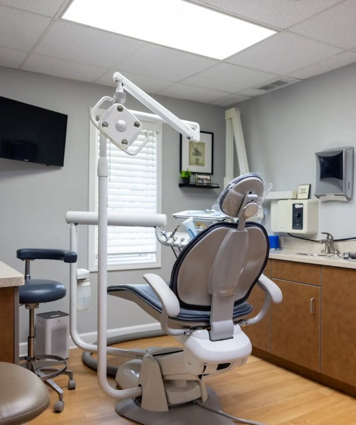 Modern dental operatory chair with overhead light and equipment in professional office setting.
